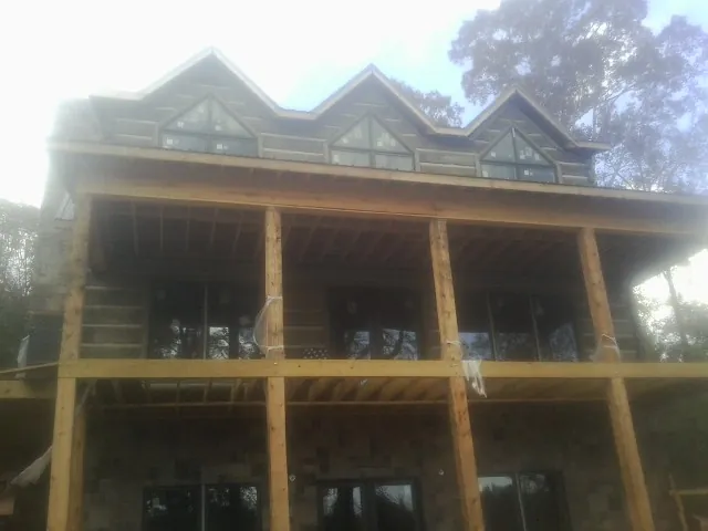 Dormers and porch framing on a large log home under construction — Roof Coating work by our crew in Rio Medina
