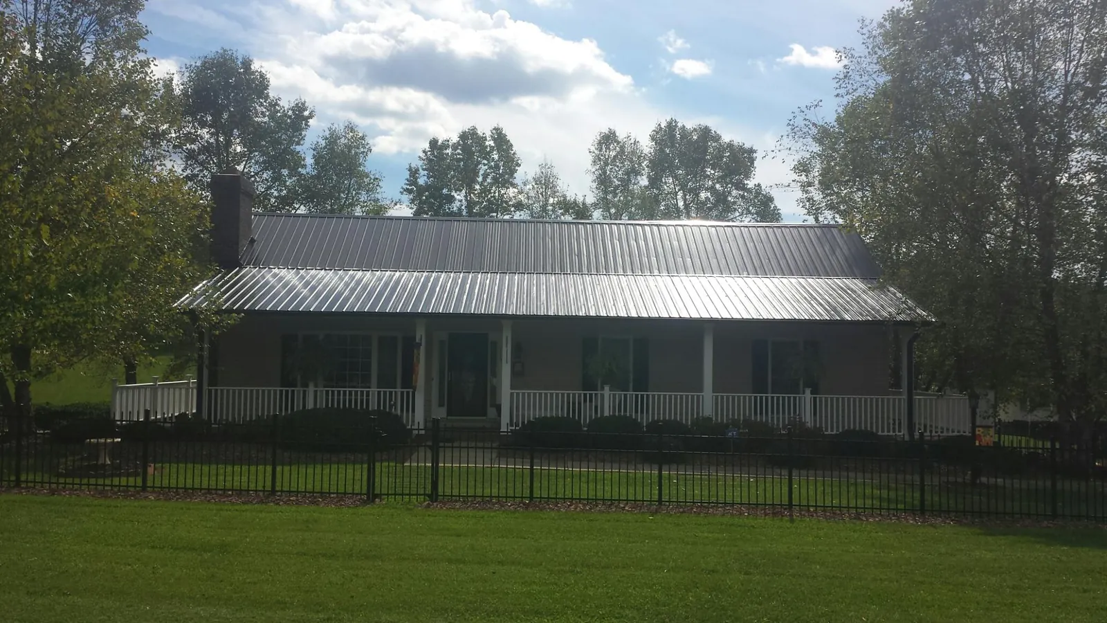 Gray metal roof on a brick ranch with a full width front porch — Gutter Guard Installation work by our crew in Rio Medina