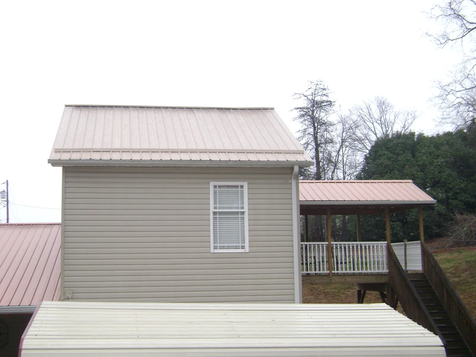 Tan metal roofs on a two story addition and attached porch, from a Roof Replacement job in Rio Medina