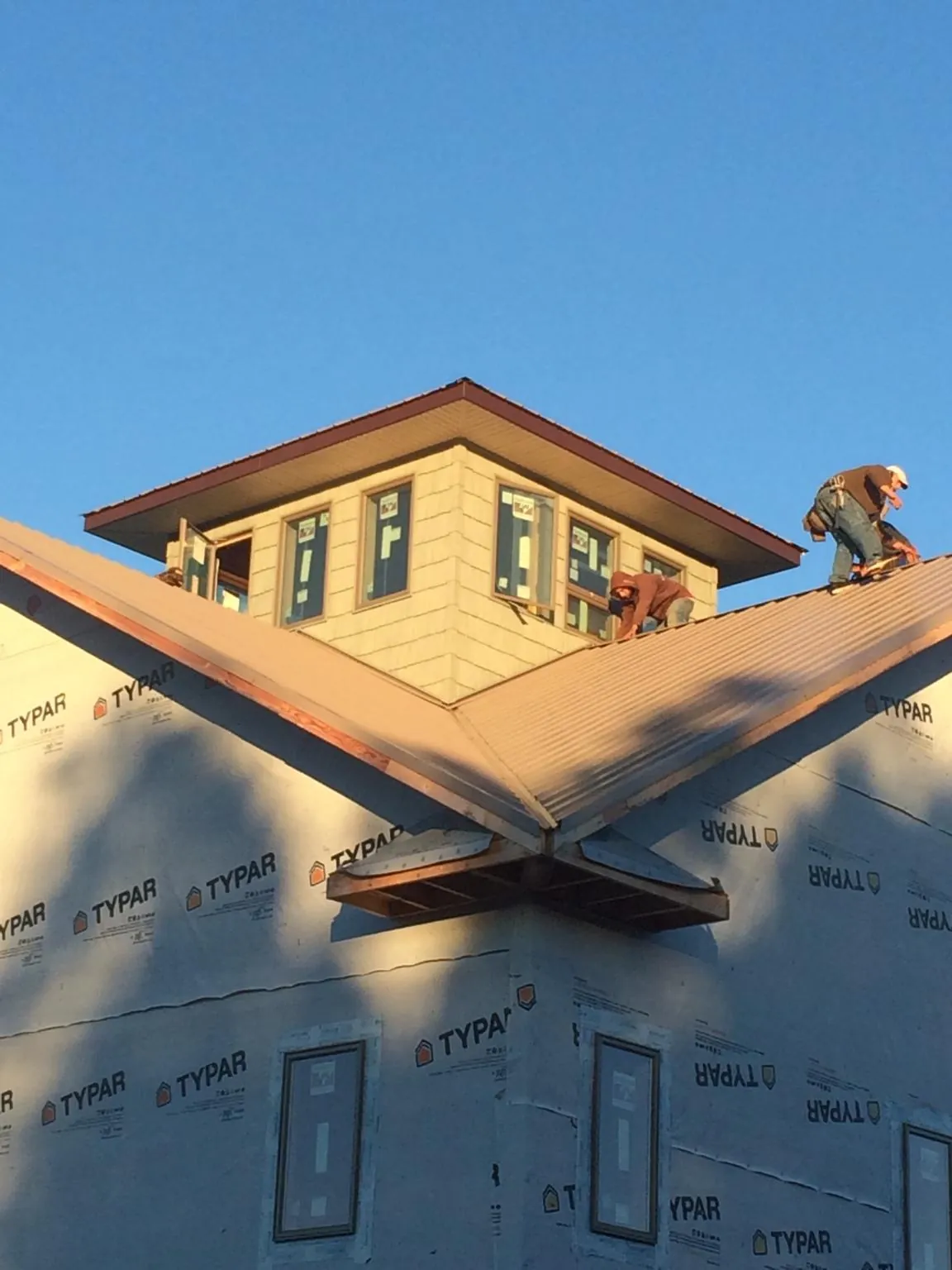 Roofers working around a rooftop cupola on a new metal roof at sunset — Roof Waterproofing in Rio Medina by Roofing Brothers